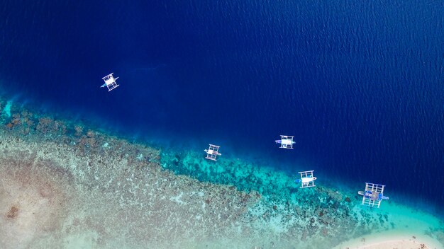 Вид с воздуха на песчаный пляж с туристами, купающимися в красивой чистой морской воде на пляже Сумилонского острова, приземляясь около Ослоба, Себу, Филиппины. - Увеличьте цвет обработки.