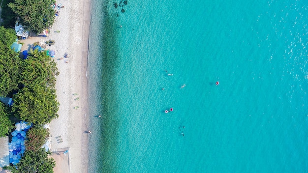 Aerial view of sandy beach with tourists swimming.