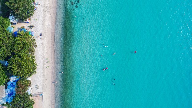 Aerial view of sandy beach with tourists swimming.