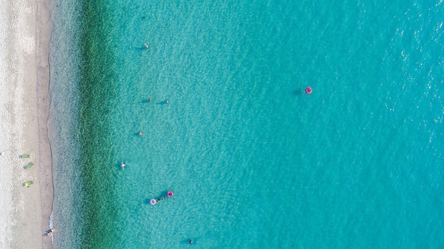 Aerial view of sandy beach with tourists swimming.