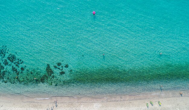 Aerial view of sandy beach with tourists swimming.