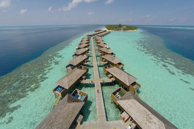 Aerial view of a tropical island in turquoise water. Luxurious over-water villas on tropical island resort maldives for holiday vacation background concept -Boost up color Processing.