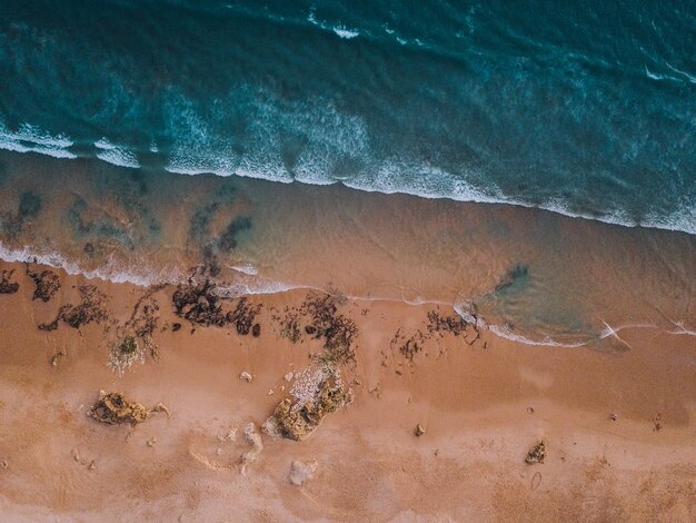 Aerial view of the waves of the sea and the sandy shore