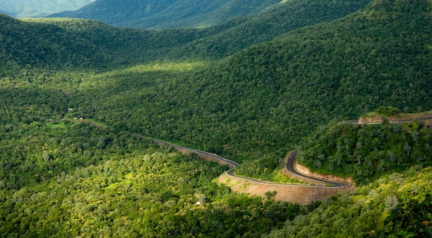 Вид с воздуха на извилистую дорогу в живописных зеленых горах