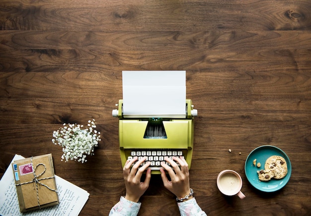 Foto gratuita vista aerea di una donna che scrive su una carta in bianco della retro macchina da scrivere