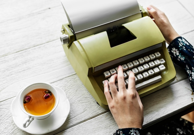 Foto gratuita vista aerea di una donna che scrive su una carta in bianco della retro macchina da scrivere