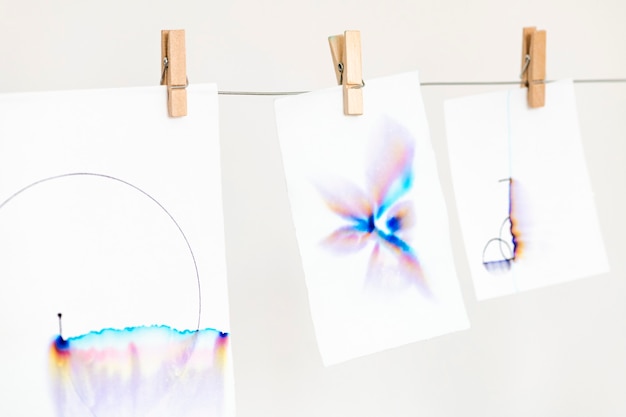 Free photo aesthetic chromatography art on white papers hanging on a rope