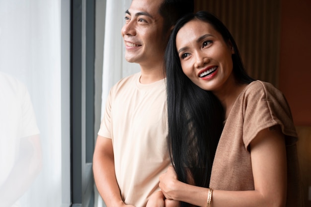 Affectionate couple embracing and looking through the window at home