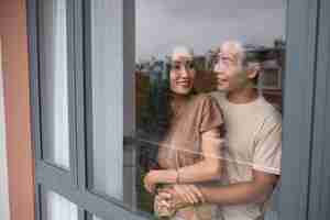 Free photo affectionate couple embracing and looking through the window at home