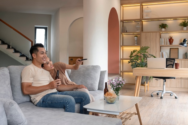 Affectionate couple at home having food in bowl and beer