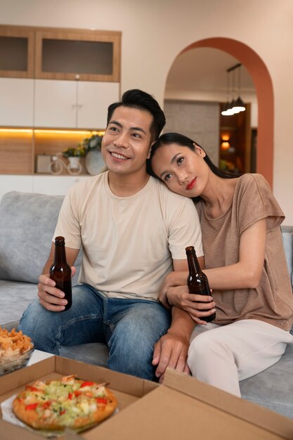 ピザとビールを持っている家で愛情のこもったカップル