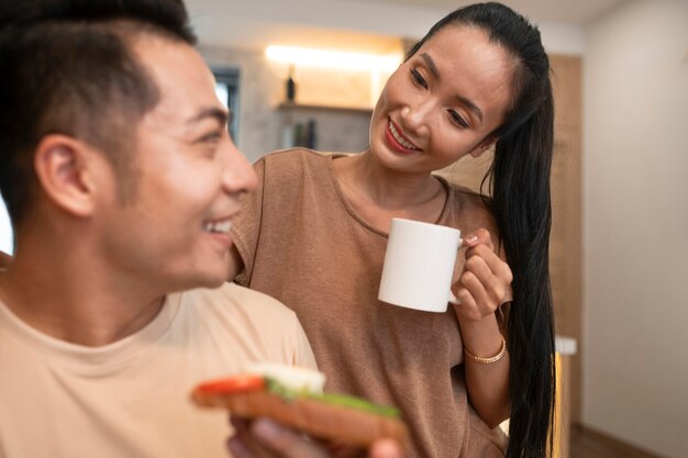 Foto gratuita coppia affettuosa a casa con panino e caffè