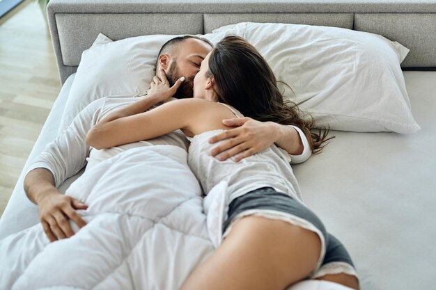 愛情のこもったカップルが自宅のベッドに横になってキス