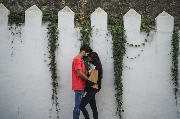 Free photo affectionate couple standing by a decorated wall