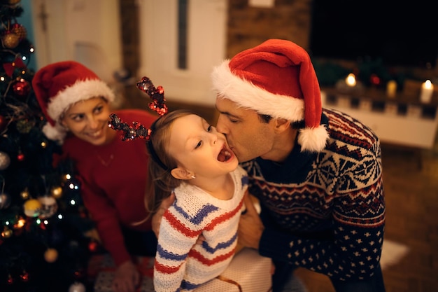 Нежный отец целует дочь в канун Рождества дома