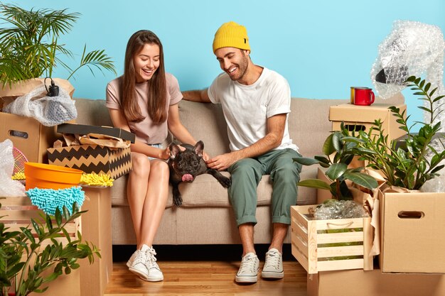 Affectionate young couple sitting on the couch surrounded by boxes