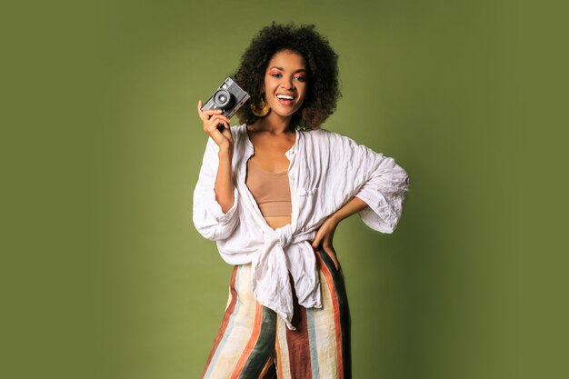 Afican woman holding retro photo camera and laughing.