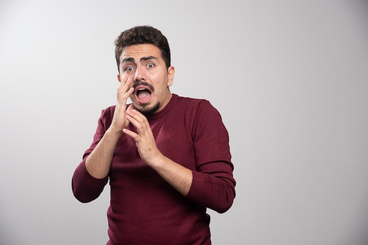 Free Photo an afraid brunette man over a gray wall.