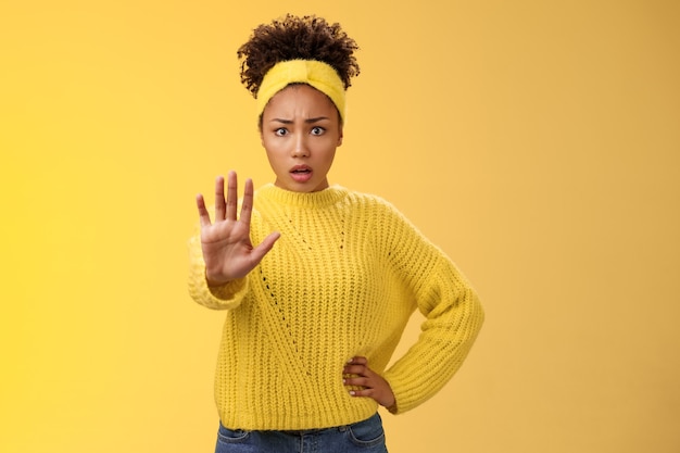 Afraid shocked insecure woman trying show voice be brave extend arm enough stop refusal gesture look frightened insecure unconfident rejecting declining offensive proposal, yellow background.