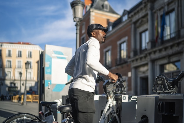 乗るために公共の自転車を取っているアフリカ系アフリカ人の男性