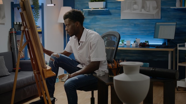 African american adult making fine art sitting in artwork studio