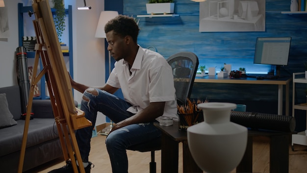 Афро-американский взрослый делает изобразительное искусство, сидя в художественной студии