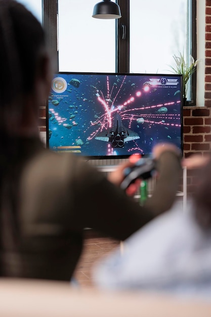 African american adult playing video games with tv console, enjoying leisure activity with friends at home. Person having fun with shooting game and competition, television gaming.