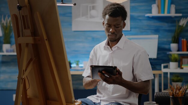 Афро-американский взрослый с художественными навыками, использующий цифровой планшет