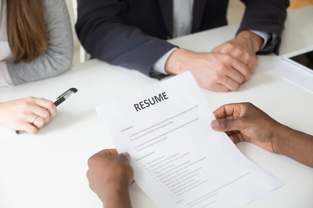 African-american applicant holding resume at job interview, close up view