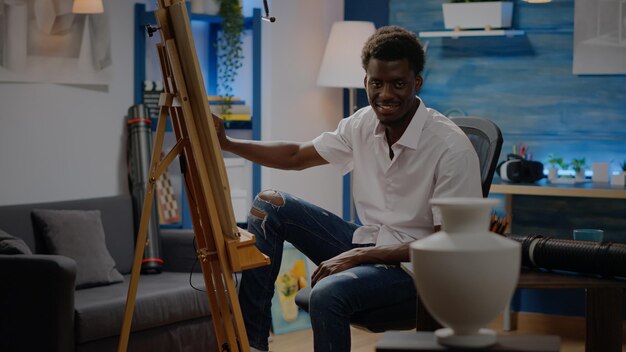 ワークショップの創造性スタジオでデザインを描くための花瓶を見ているアフリカ系アメリカ人のアーティスト。プロの傑作と美術プロジェクトのためのインスピレーションを使用して黒人の若い男。芸術的な大人
