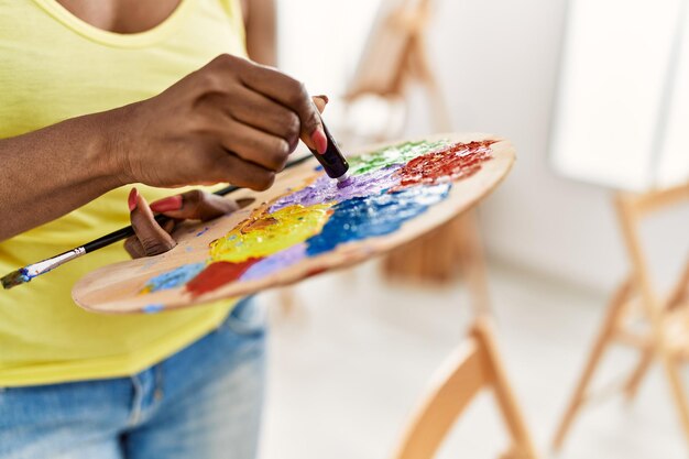 Афро-американская художница смешивает цвета на палитре в художественной студии.