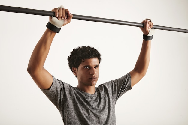 African American athlete wearing technical t-shirt and cross fitness hand protection grabbling carbon pullup bar isolated on white