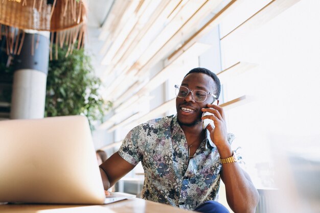 African american business man with phone and laptop in a cafe