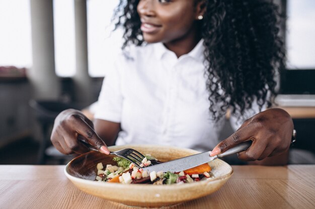 Афроамериканец деловая женщина, едят салат в кафе крупным планом