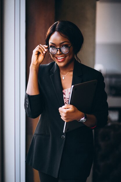 Афроамериканец бизнес женщина Холдинг ноутбук и стоя у окна