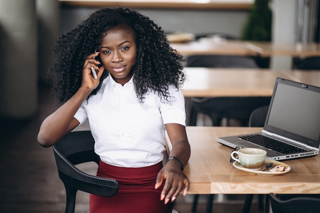 Donna afroamericana di affari che parla sul telefono in un caffè