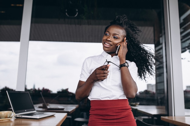 African american business woman with computer and phone in a cafe