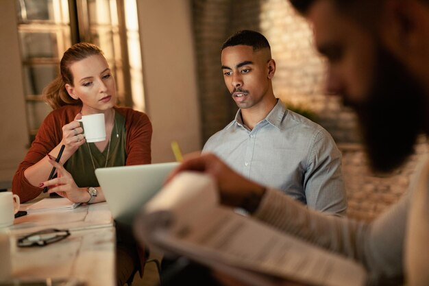 African American businessman and his female colleagues working on laptop in the office