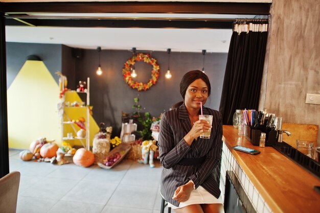 Free photo african american businesswoman drinking cocktail lemonade in cafe at the bar black girl having rest with mobile phone