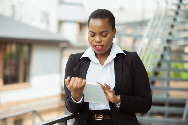African American businesswoman in office attire smiling, looks confident and happy, busy
