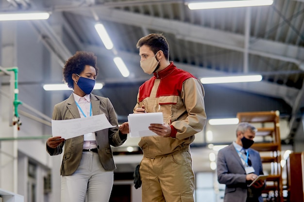 african american businesswoman talking to a worker at woodworking industrial facility