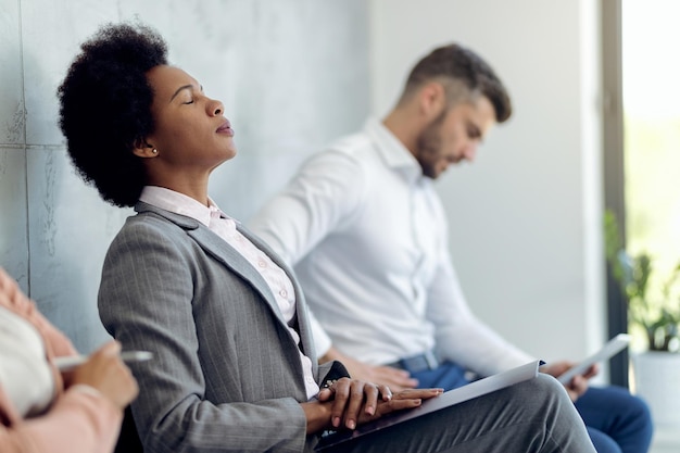 Foto gratuita donna d'affari afroamericana che cerca di concentrarsi mentre aspetta un colloquio di lavoro