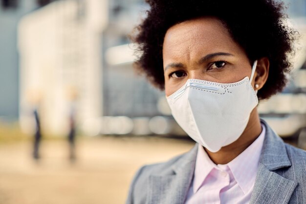 屋外で保護フェイスマスクを持つアフリカ系アメリカ人の実業家