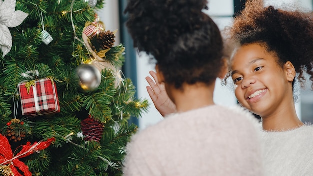 African American child decorated with ornament on Christmas tree