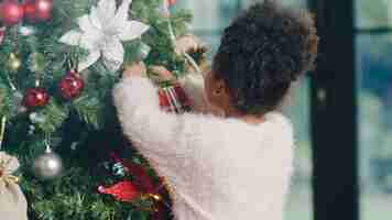 Free photo african american child decorated with ornament on christmas tree