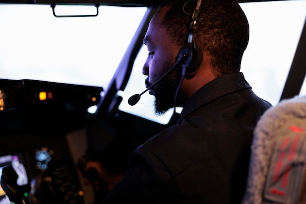 African american copilot flying airplane in cockpit with captain, using lever and power buttons to takeoff. Aircrew member pushing dashboard control command switch to fly. Close up.