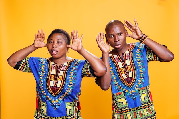 Free photo african american couple fooling around and showing silly grimace together portrait cheerful man and woman pair having fun posing with comic face expression and looking at camera