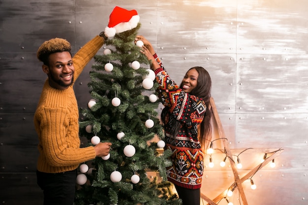 クリスマスツリーにおもちゃをぶら下げているアフリカ系アメリカ人のカップル