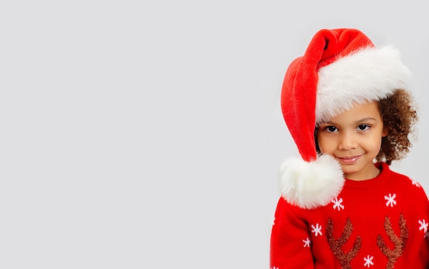 Афро-американский милый ребенок в новогодней шапке и тематическом костюме на белом фоне Premium Фотографии