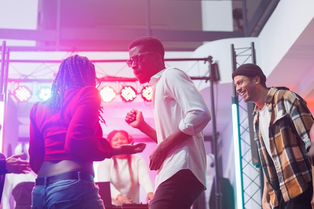 African american dancers couple improvising moves at live electronic music discotheque in nightclub. Energetic young man and woman dancing and partying on dancefloor in club